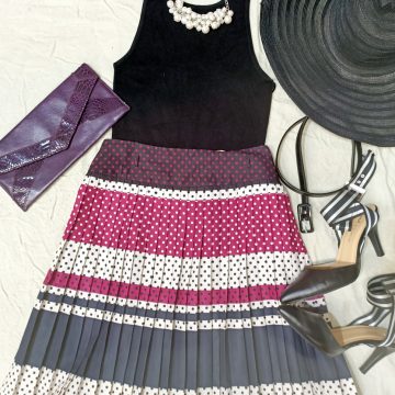 Flat lay of black and pink dress, summer hat, metallic purple clutch purse and black pumps