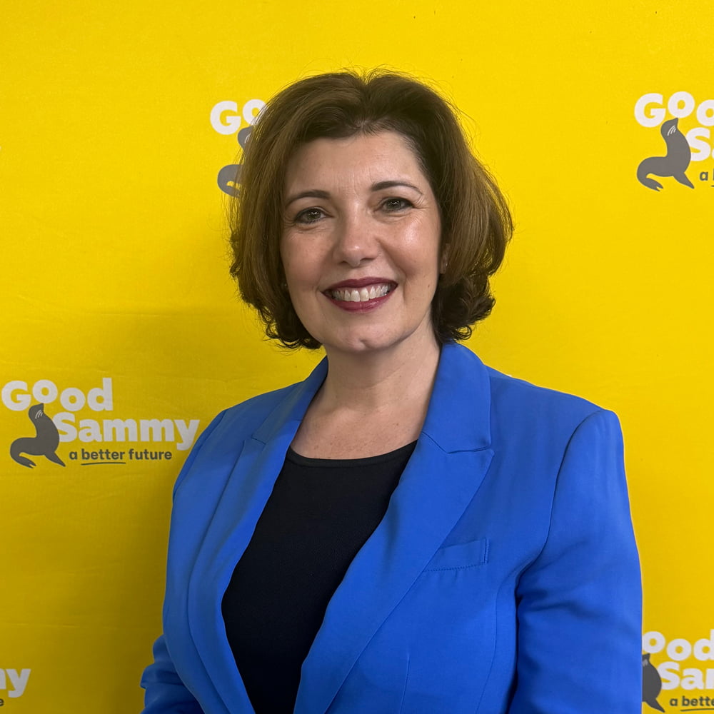 Sonia Nolan smiling at camera in front of yellow background.