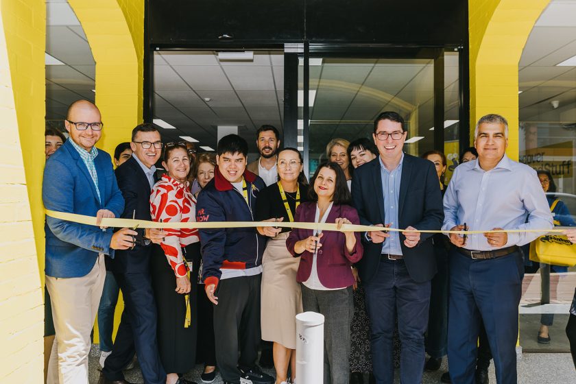 A group of people standing outside the Good Sammy Leederville store, smiling for the camera and preparing to cut a yellow ribbon.